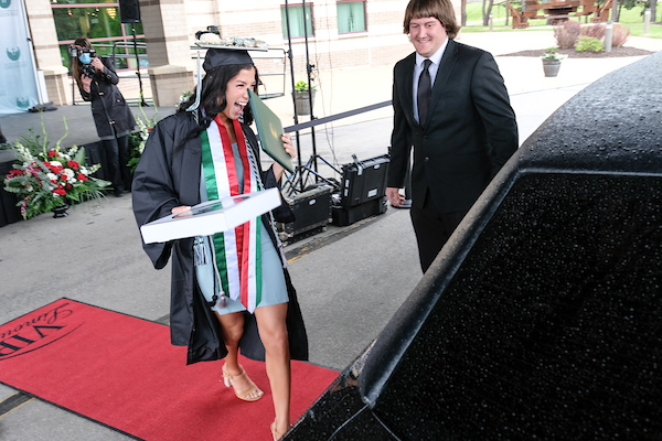 Una estudiante mostrando su diploma a su familia después de graduarse.
