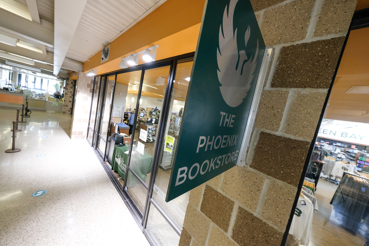 An exterior shot of the Phoenix Bookstore, with a large green and brushed silver sign reading "The Phoenix Bookstore