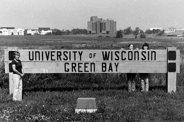 Black and white photo of people with a UW-Green Bay sign