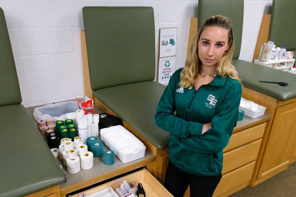 Athletic training graduate student posing by althetic training supplies