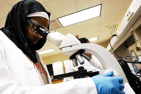 Student in Hijab looks into microscope