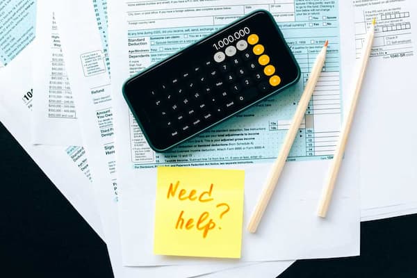 "Need Help?" post it note placed on tax paper