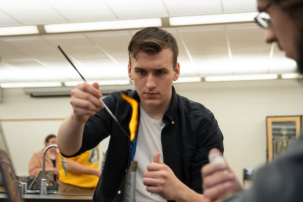 Students using a bunsen burner in a lab experiment