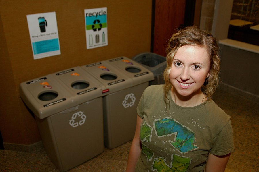 Student standing by recycling cans.