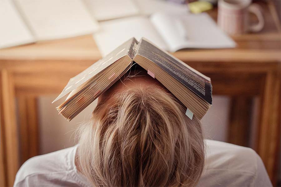 Student with a book over her face