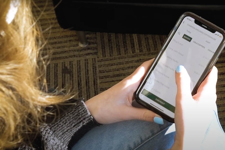 An over-the-shoulder shot of a student browsing the UWGB Dining App on their mobile device
