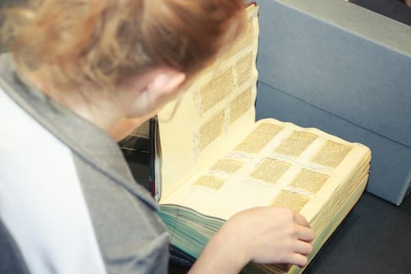 Student referencing newspaper clippings in an archives scrapbook