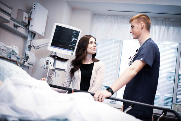 Brianna, an MSN grad at Aurora, talks with a nursing student in a hospital room.