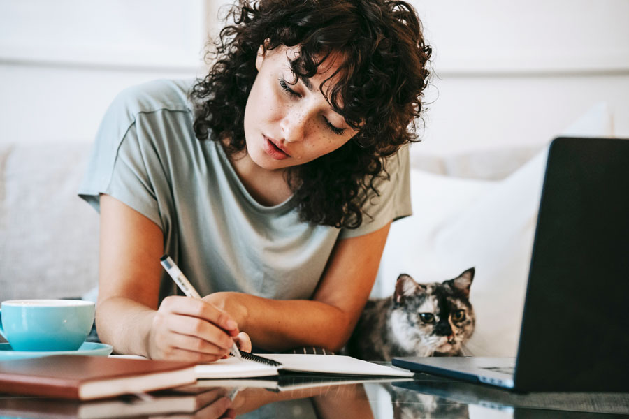 Woman attends online class at home with cat off to the side