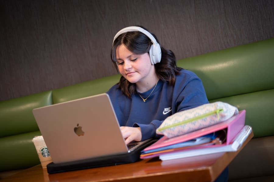 Female student studying on laptop with headphones