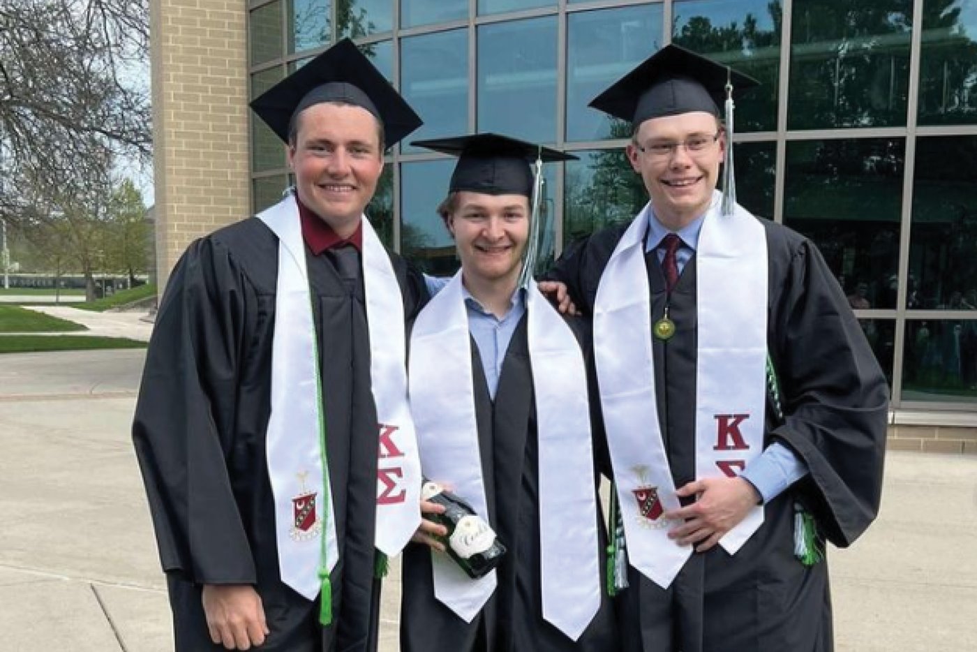 Kappa Sigma brothers pose in their caps, gowns and fraternity regalia at commencement