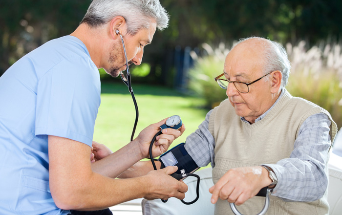 male healthcare worker taking pulse of elderly resident