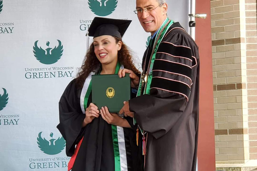 Nadia and Chancellor Mike take photo with diploma at graduation