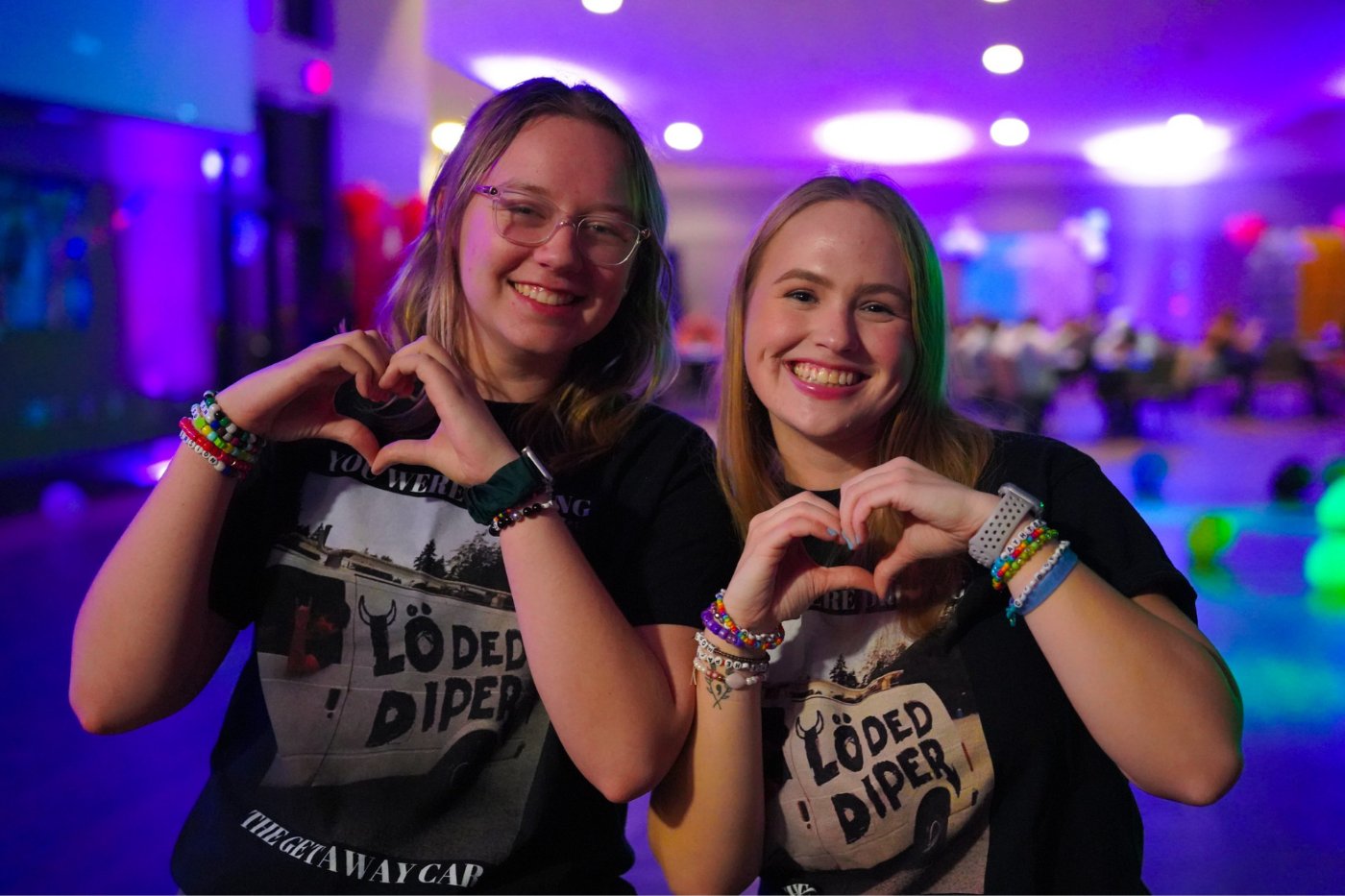 Two sorority members hold up heart hands and smile at the camera at a Taylor Swift-themed dance party