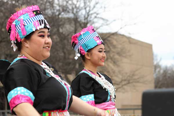 Two Hmong students dance in traditional wear and multicultural festival
