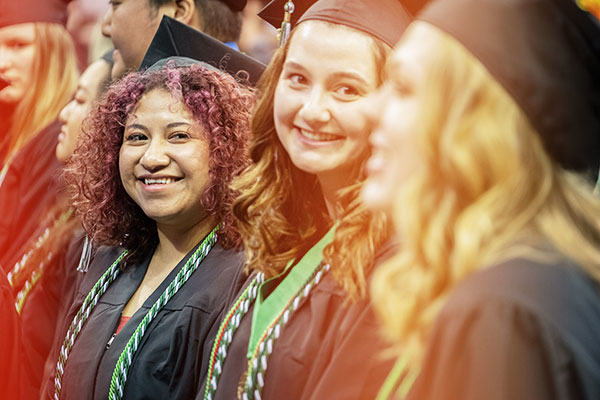 A UWGB student at commencement smiles at her fellow graduates