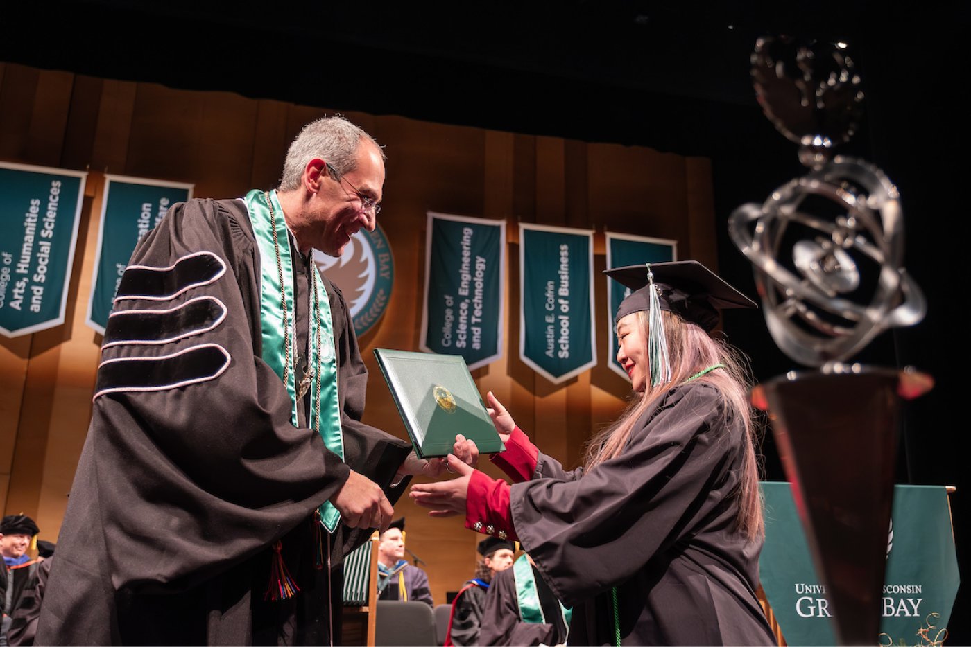 A student receives their diploma from the Chancellor