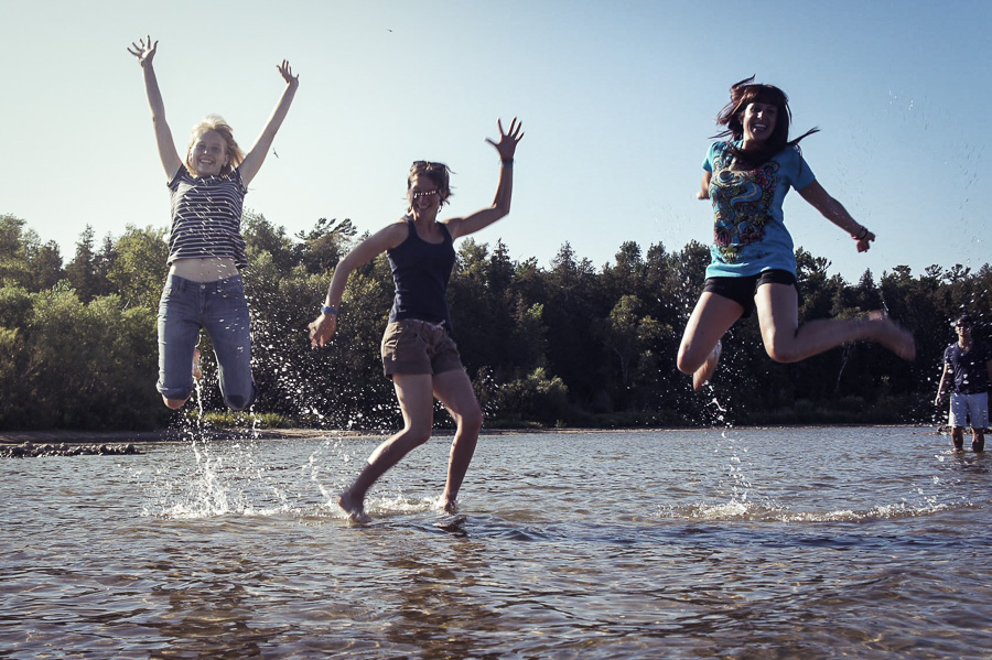 Three UW-Green Bay students jumping in shallow water of the bay in Door County