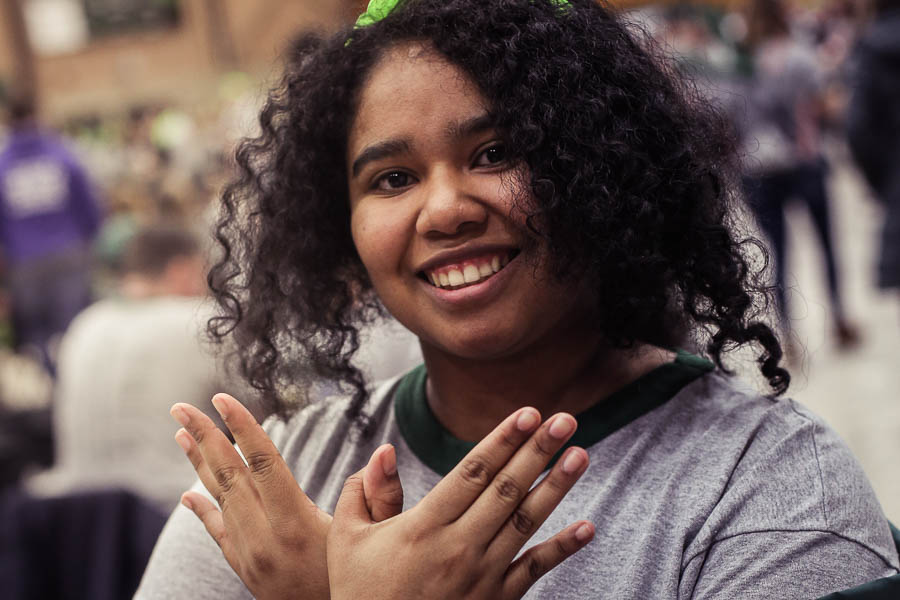 smiling student makes a phoenix symbol with her hands