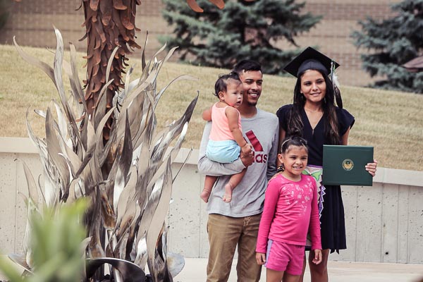 Graduate poses with her young family on campus