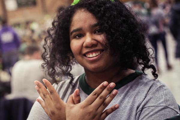 Student making a Phoenix symbol with her hands.