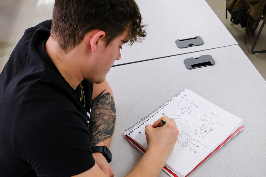 A calculus student takes notes in class.