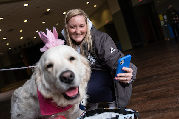 A student takes a selfie with a dog.