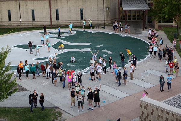 Student painting a large Phoenix on campus