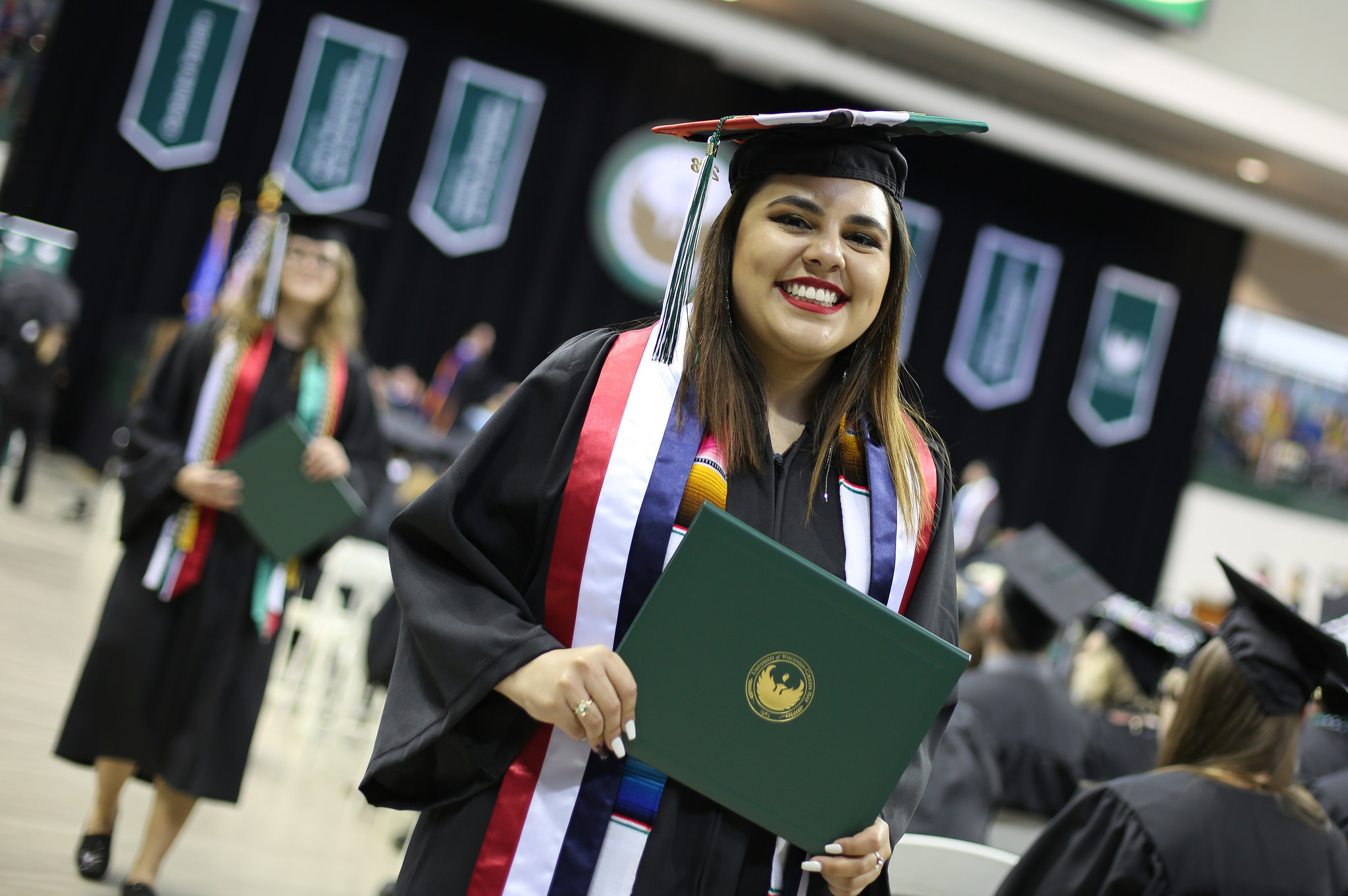 student holding diploma walking out of graduation ceremony