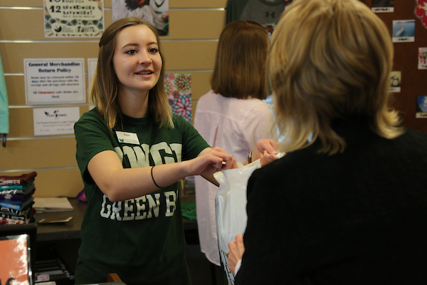 A student worker hands a customer their purchase at the Phoenix Bookstore.