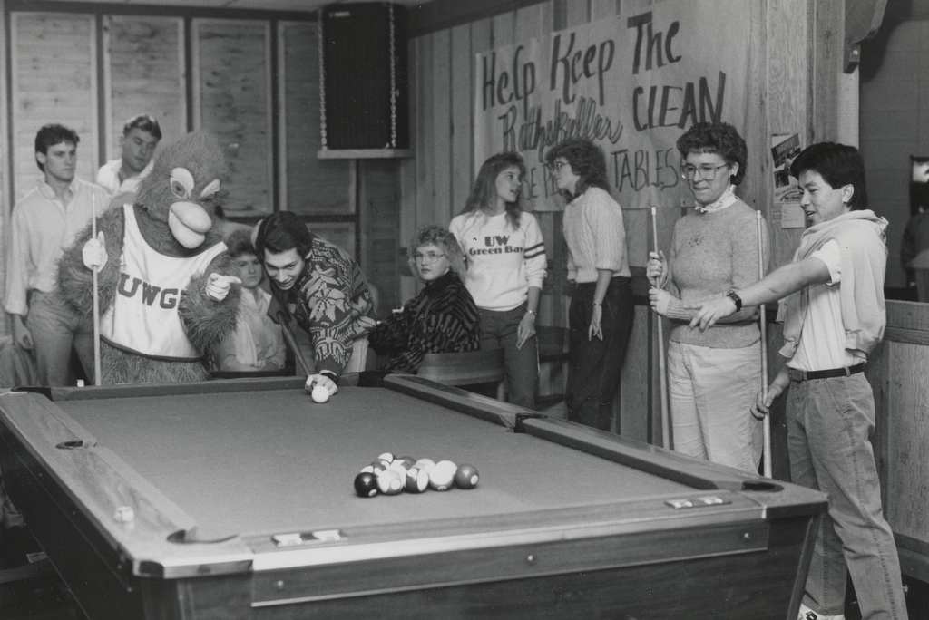 Black and white photograph of people playing pool with the Phoenix mascot