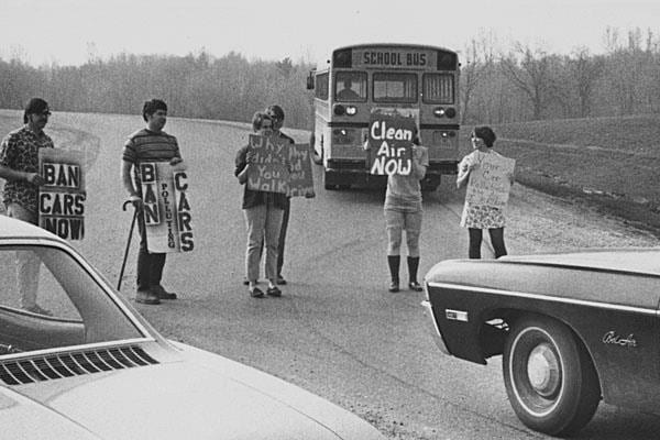 1970s students on road protesting between cars and bus with "Ban car" and "Clean air now" signs