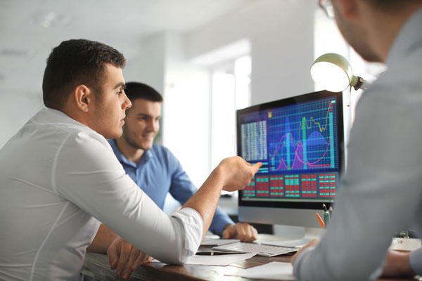 two men looking at computer screen containing data analytics