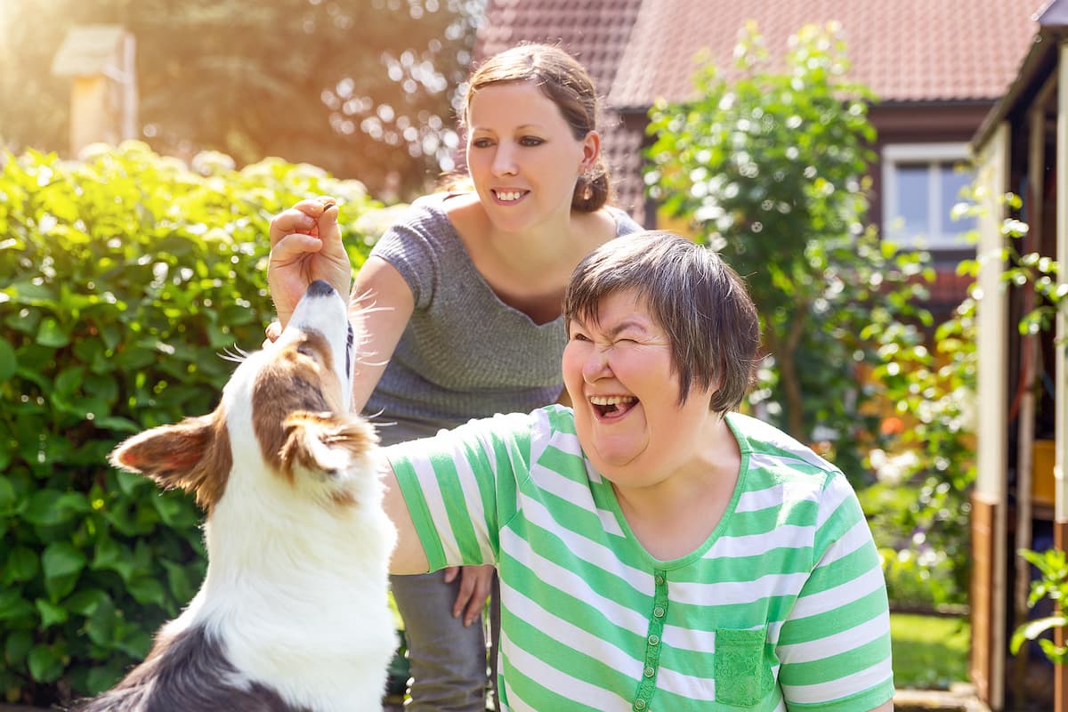 Mentally disabled woman feeding a dog with younger woman