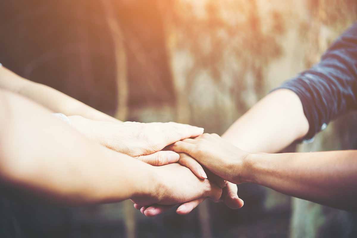 close up of hands comforting and supporting another person