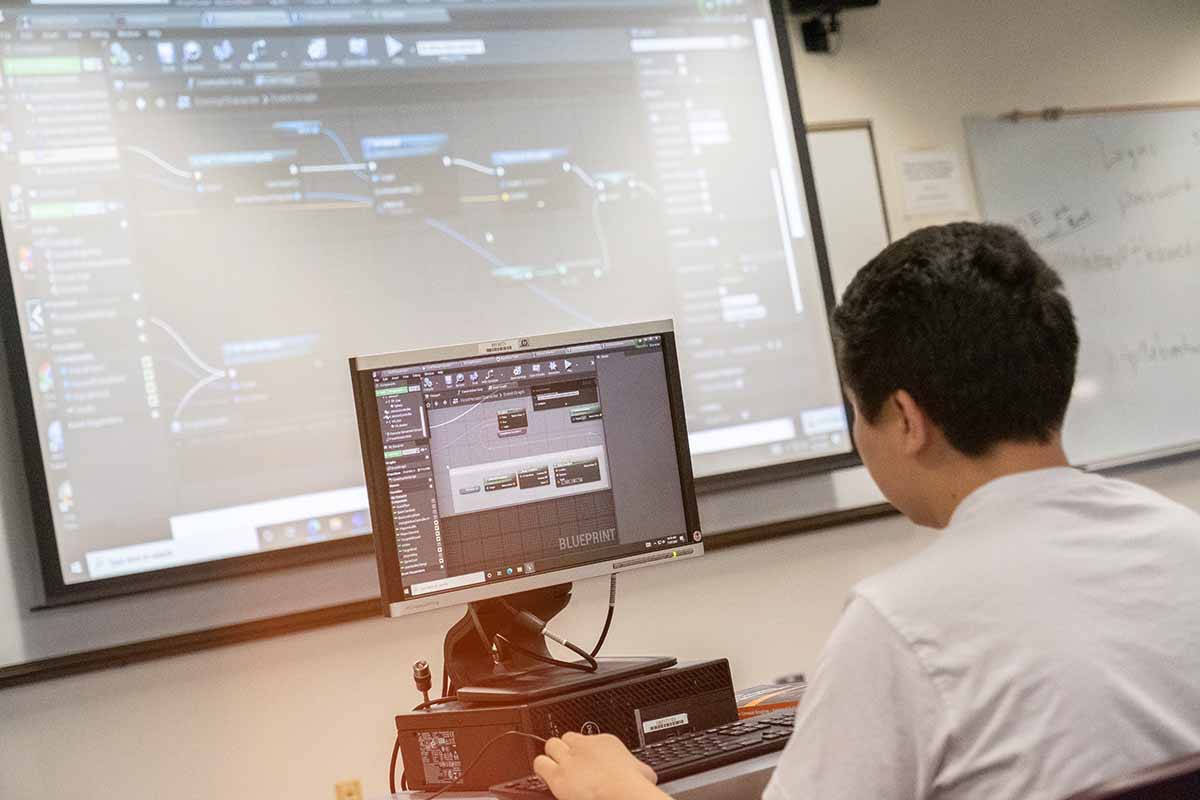 student coding video game with large screen