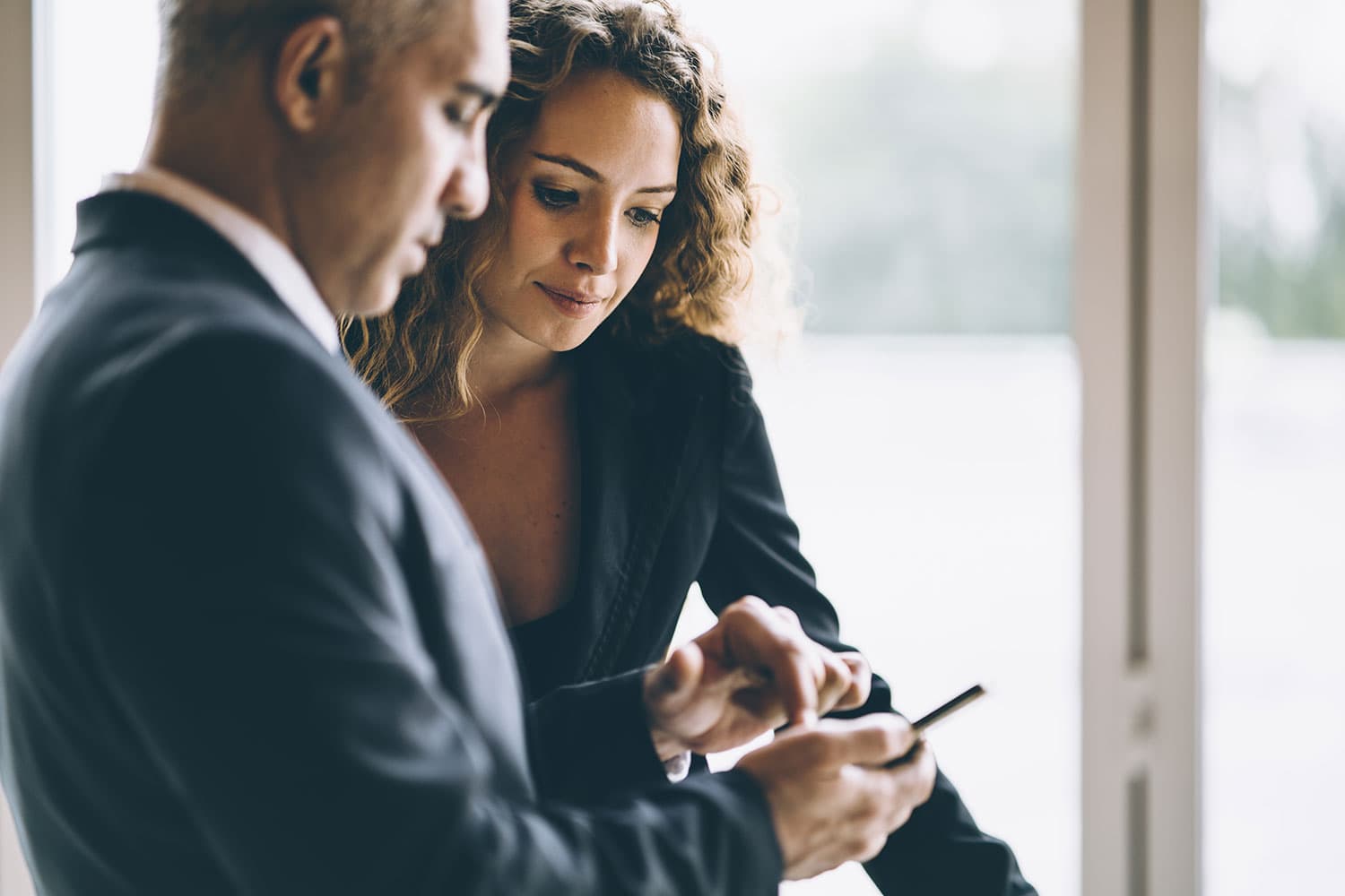 Business woman and man looking at phone together