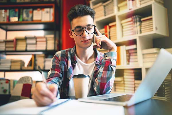 teenager studying in a coffeeshop with bookcases in background