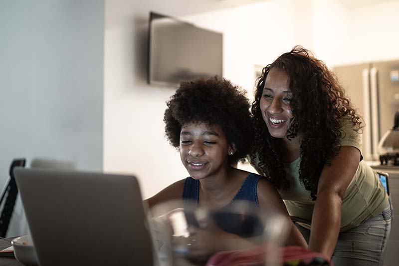 mom with teen looking at laptop screen together