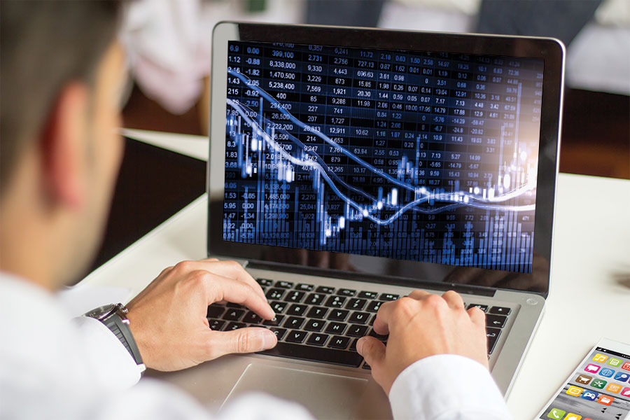 A man on his laptop looking over a stock graphic