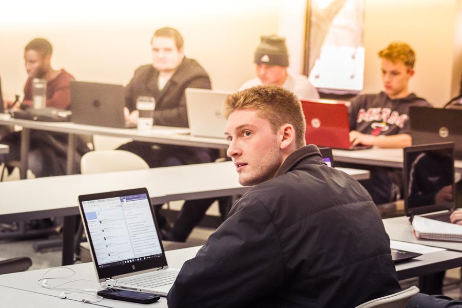 Student seated in class, using a laptop