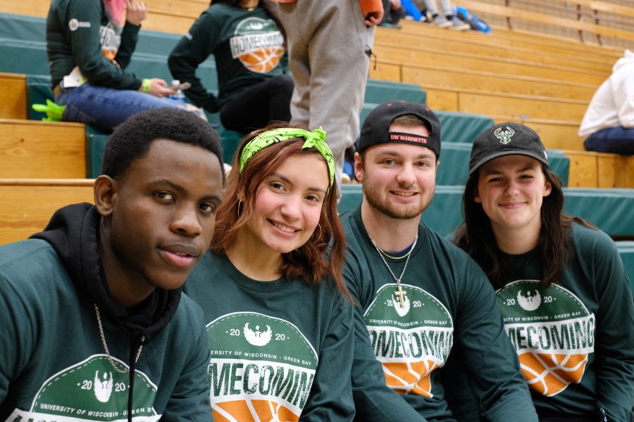 Four Alumni on bleachers