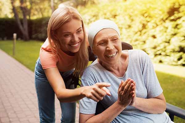 woman caregiver pointing to something while with senior woman outside