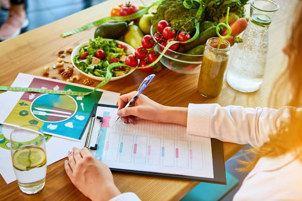 Dietition working on nutrition plan with bowl of fruits and veggies