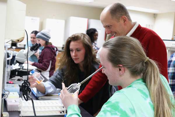 Professor Brian Merkel works with students in lab