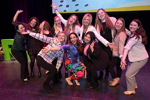 Mariana posing on stage with a group of women