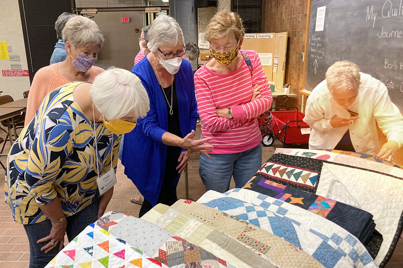 Group of lifelong learning members looking at quilting examples