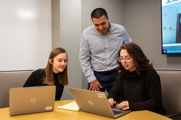 Two students work at Georgia Pacific Intership while supervisor looks on