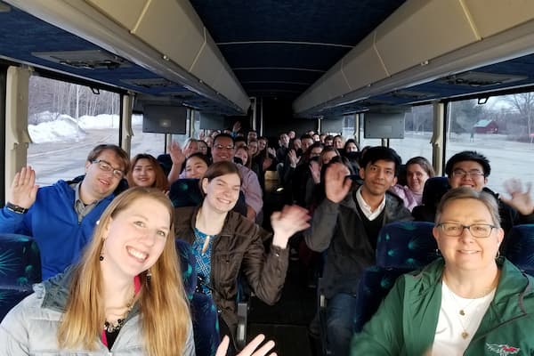 Management students smile for photo on bus on their way to business management tour