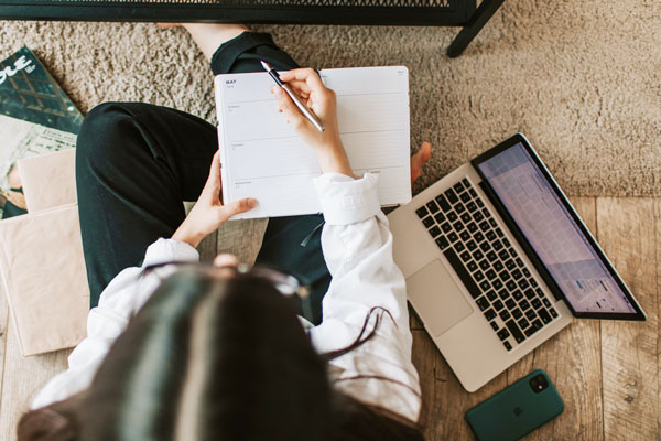 Overhead view of student taking notes during online class